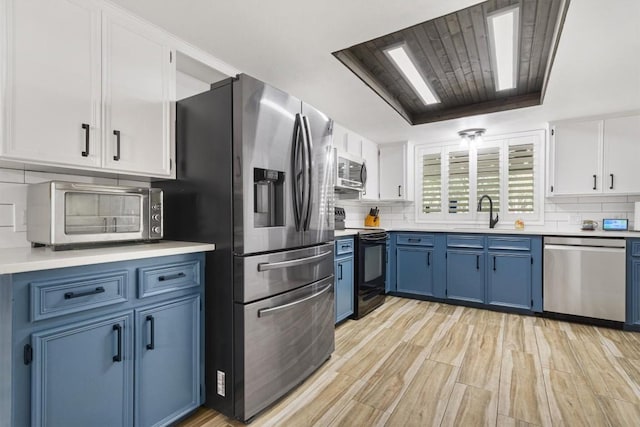 4001 Granada Dr, Georgetown, TX 78628 - kitchen featuring stainless steel appliances, blue cabinets, light countertops, and backsplash