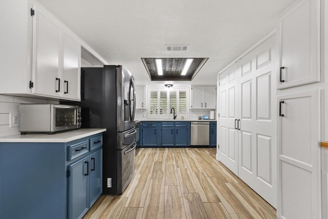 4001 Granada Dr, Georgetown, TX 78628 - kitchen with blue cabinetry, dishwasher, fridge with ice dispenser, backsplash, and light countertops