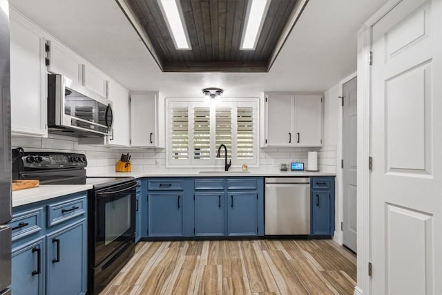 4001 Granada Dr, Georgetown, TX 78628 - kitchen featuring stainless steel appliances, blue cabinets, white cabinets, backsplash, and light wood-style floors