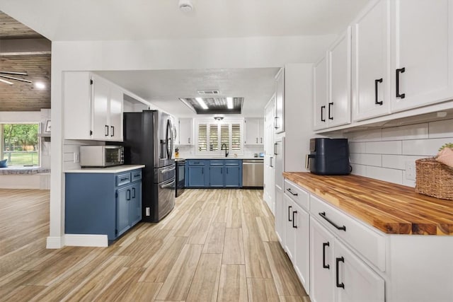 4001 Granada Dr, Georgetown, TX 78628 - kitchen featuring appliances with stainless steel finishes, blue cabinets, plenty of natural light, and wooden counters