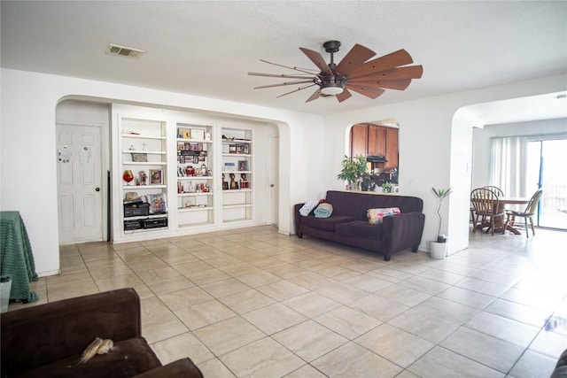 13604 Gilwell Dr, Del Valle, TX 78617 - living area featuring arched walkways, light tile patterned floors, built in shelves, and a textured ceiling