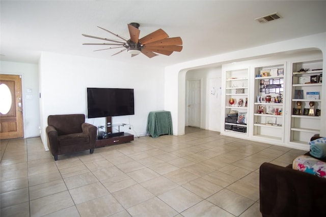 13604 Gilwell Dr, Del Valle, TX 78617 - living area featuring arched walkways, light tile patterned floors, ceiling fan, and built in shelves