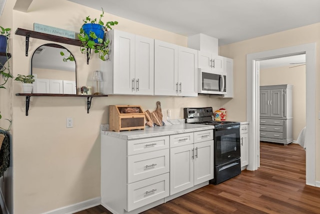 1215 Bois Darc St, Lockhart, TX 78644 - kitchen featuring black range with electric cooktop, stainless steel microwave, dark wood-type flooring, and white cabinetry
