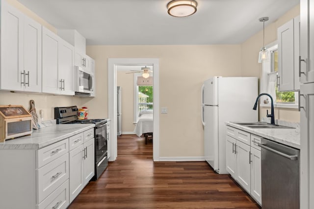 1215 Bois Darc St, Lockhart, TX 78644 - kitchen with white appliances, dark wood finished floors, white cabinets, pendant lighting, and a ceiling fan