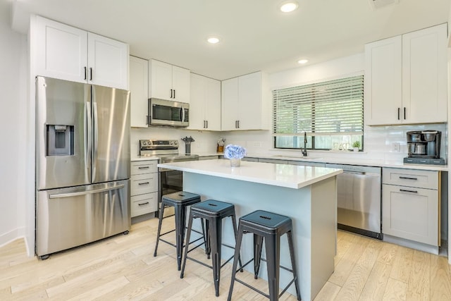 6904 Rusty Fig Dr, Austin, TX 78750 - kitchen featuring appliances with stainless steel finishes, a kitchen breakfast bar, light wood-type flooring, light countertops, and backsplash