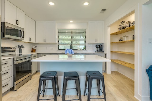 6904 Rusty Fig Dr, Austin, TX 78750 - kitchen featuring stainless steel appliances, a kitchen bar, light countertops, white cabinetry, and recessed lighting