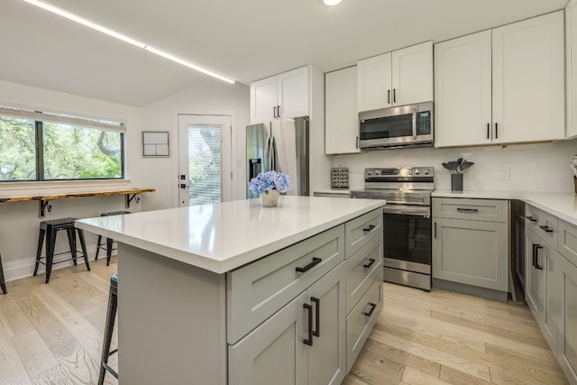 6904 Rusty Fig Dr, Austin, TX 78750 - kitchen with stainless steel appliances, light wood-type flooring, light countertops, a kitchen island, and gray cabinets