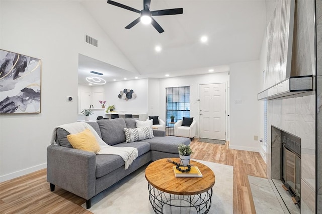 12307 Marogot Run, Austin, TX 78758 - living area featuring light wood finished floors, a tiled fireplace, a ceiling fan, high vaulted ceiling, and recessed lighting