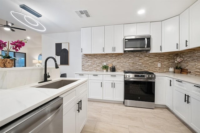 12307 Marogot Run, Austin, TX 78758 - kitchen with stainless steel appliances, tasteful backsplash, white cabinets, a ceiling fan, and recessed lighting