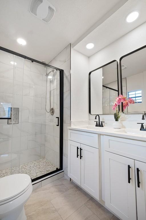 12307 Marogot Run, Austin, TX 78758 - bathroom with a shower stall, double vanity, and recessed lighting