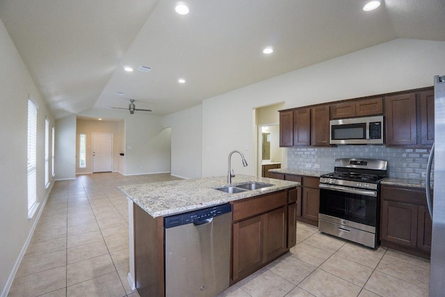 5865 Urbano Bnd, Round Rock, TX 78665 - kitchen with appliances with stainless steel finishes, vaulted ceiling, light tile patterned floors, backsplash, and light stone counters