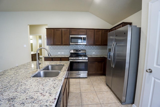 5865 Urbano Bnd, Round Rock, TX 78665 - kitchen featuring stainless steel appliances, lofted ceiling, decorative backsplash, light stone counters, and dark brown cabinets
