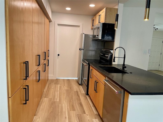 5809 Cherry Creek Dr, Austin, TX 78745 - kitchen with appliances with stainless steel finishes, dark countertops, light wood-style floors, a peninsula, and recessed lighting