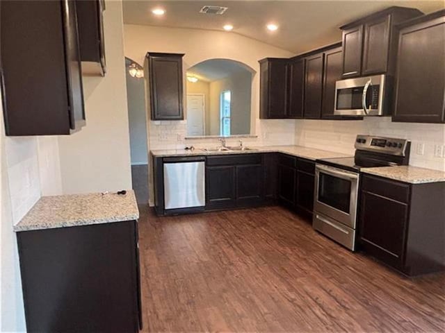 103 Beth Ann Loop, Taylor, TX 76574 - kitchen featuring appliances with stainless steel finishes, arched walkways, tasteful backsplash, dark wood finished floors, and vaulted ceiling