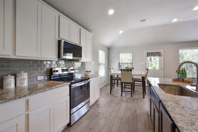 21510 Paine Ave, Lago Vista, TX 78645 - kitchen with appliances with stainless steel finishes, healthy amount of natural light, vaulted ceiling, tasteful backsplash, and recessed lighting