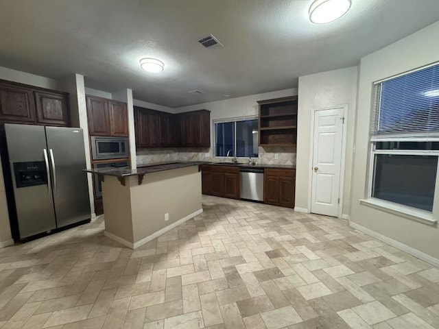 10204 Tenava Ct, Austin, TX 78726 - kitchen featuring appliances with stainless steel finishes, tasteful backsplash, open shelves, dark countertops, and a breakfast bar