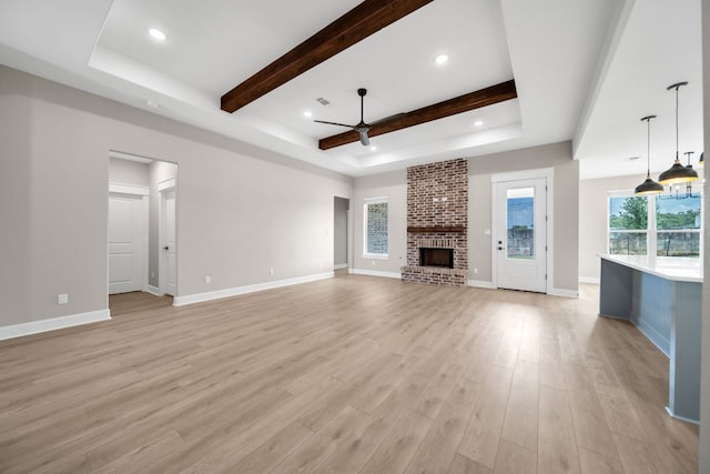122 Buffalo Ridge Rd, Giddings, TX 78942 - unfurnished living room featuring ceiling fan, beam ceiling, a brick fireplace, light wood-style floors, and recessed lighting