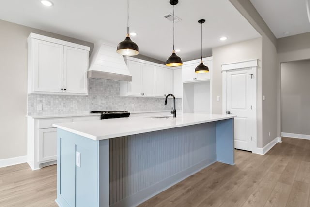 122 Buffalo Ridge Rd, Giddings, TX 78942 - kitchen featuring custom range hood, decorative backsplash, light wood-style flooring, white cabinets, and recessed lighting