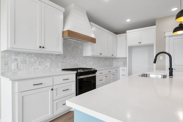122 Buffalo Ridge Rd, Giddings, TX 78942 - kitchen with gas range, custom range hood, light countertops, white cabinetry, and recessed lighting
