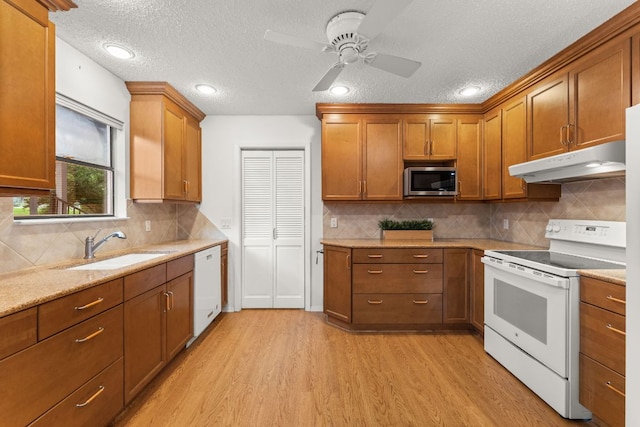 605 Flamingo Blvd, Lakeway, TX 78734 - kitchen featuring white appliances, under cabinet range hood, light wood-type flooring, a textured ceiling, and brown cabinetry