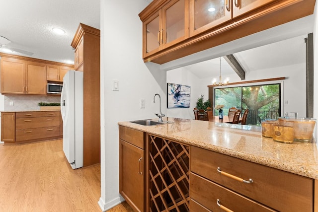 605 Flamingo Blvd, Lakeway, TX 78734 - kitchen with freestanding refrigerator, stainless steel microwave, light wood-type flooring, light stone countertops, and beamed ceiling