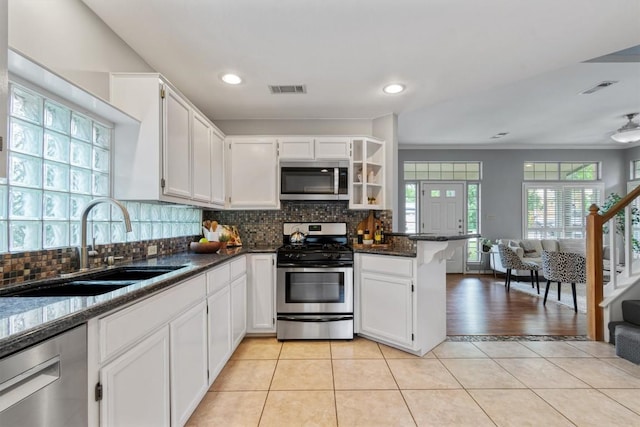 2207 Shoalmont Dr, Austin, TX 78756 - kitchen with appliances with stainless steel finishes, white cabinets, a peninsula, decorative backsplash, and recessed lighting