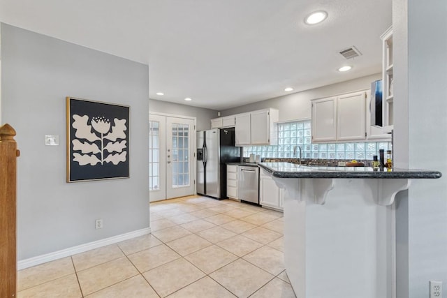 2207 Shoalmont Dr, Austin, TX 78756 - kitchen with stainless steel appliances, white cabinetry, a peninsula, backsplash, and light tile patterned floors
