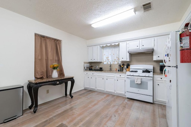 1106 Saucedo St, Austin, TX 78721 - kitchen with white appliances, white cabinets, light wood finished floors, under cabinet range hood, and a textured ceiling