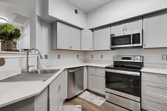2320 Gracy Farms Ln Unit 918, Austin, TX 78758 - kitchen with appliances with stainless steel finishes, wood finished floors, light countertops, and gray cabinets