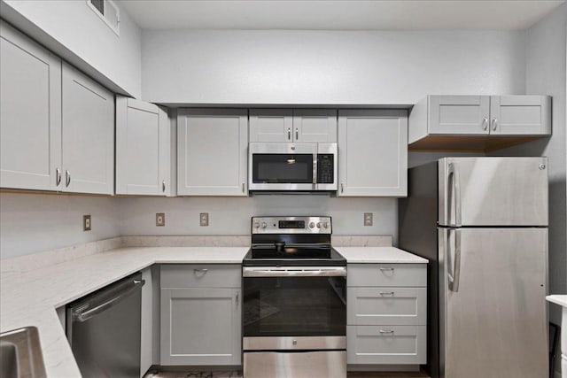 2320 Gracy Farms Ln Unit 918, Austin, TX 78758 - kitchen featuring stainless steel appliances, gray cabinets, and light stone countertops