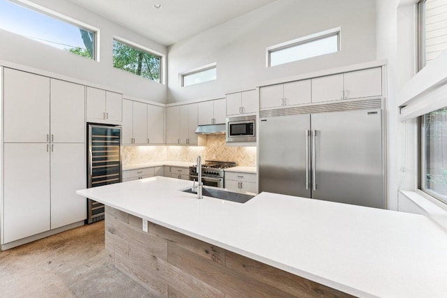 2004 Pennsylvania Ave Unit A, Austin, TX 78702 - kitchen featuring built in appliances, a towering ceiling, beverage cooler, decorative backsplash, and under cabinet range hood
