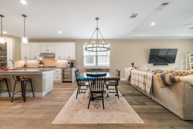 1332 Brescia Walk, Leander, TX 78641 - dining space featuring beverage cooler, light wood finished floors, recessed lighting, and a chandelier