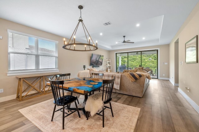 1332 Brescia Walk, Leander, TX 78641 - dining room featuring a tray ceiling, light wood-style flooring, a chandelier, and recessed lighting