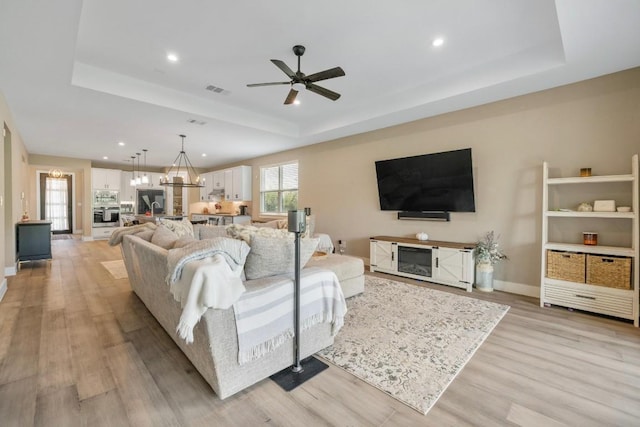 1332 Brescia Walk, Leander, TX 78641 - living area featuring a tray ceiling, light wood-type flooring, ceiling fan, recessed lighting, and a chandelier