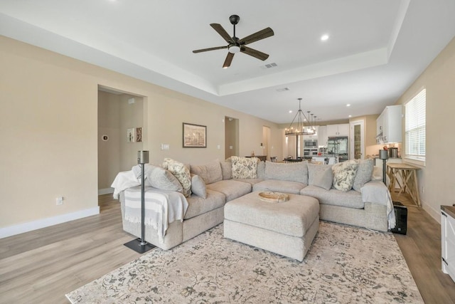 1332 Brescia Walk, Leander, TX 78641 - living area featuring a raised ceiling, light wood-style flooring, ceiling fan, a chandelier, and recessed lighting