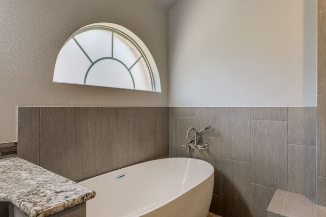 604 Cutty Trl, Lakeway, TX 78734 - bathroom featuring a soaking tub, tile walls, and a wainscoted wall