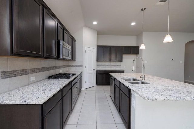 21016 Abigail Way, Pflugerville, TX 78660 - kitchen with appliances with stainless steel finishes, tasteful backsplash, light tile patterned floors, arched walkways, and dark brown cabinets
