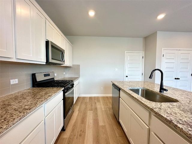 149 Gullivers Dr, Elgin, TX 78621 - kitchen featuring appliances with stainless steel finishes, light wood-type flooring, white cabinets, tasteful backsplash, and light stone countertops