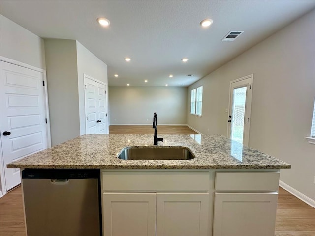 149 Gullivers Dr, Elgin, TX 78621 - kitchen featuring stainless steel dishwasher, light wood finished floors, light stone countertops, a kitchen island with sink, and open floor plan