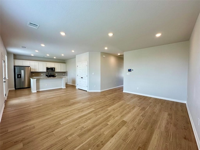 149 Gullivers Dr, Elgin, TX 78621 - unfurnished living room with light wood-type flooring and recessed lighting