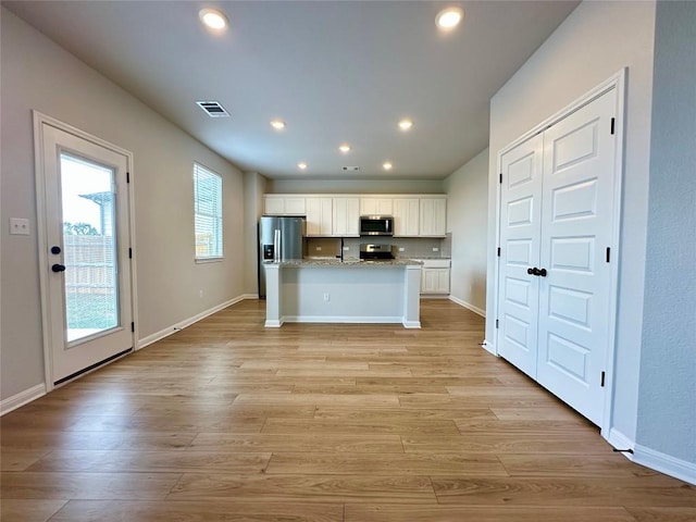 149 Gullivers Dr, Elgin, TX 78621 - kitchen featuring appliances with stainless steel finishes, white cabinets, recessed lighting, a kitchen island with sink, and light wood-style flooring