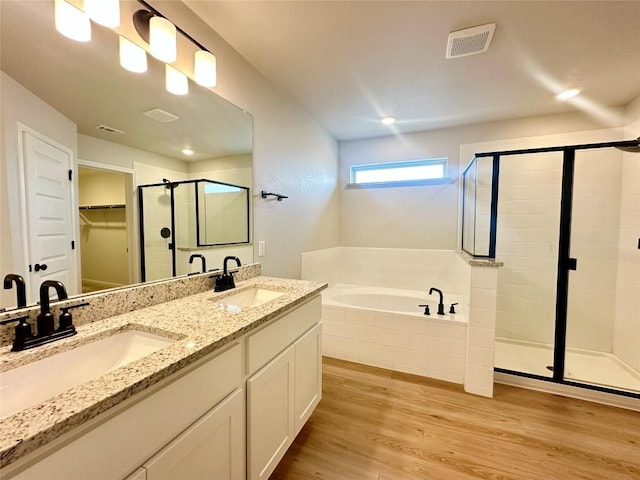 149 Gullivers Dr, Elgin, TX 78621 - bathroom featuring a stall shower, a bath, wood finished floors, double vanity, and a walk in closet