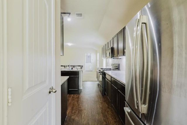 184 Voss St, Kyle, TX 78640 - kitchen featuring appliances with stainless steel finishes, dark wood finished floors, light stone counters, and vaulted ceiling