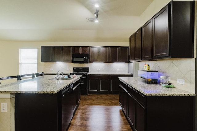184 Voss St, Kyle, TX 78640 - kitchen with black appliances, dark wood-style flooring, light stone countertops, backsplash, and an island with sink