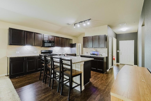 184 Voss St, Kyle, TX 78640 - kitchen featuring black appliances, decorative backsplash, dark wood finished floors, and an island with sink