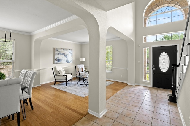 3416 Oxsheer Dr, Austin, TX 78732 - entryway with arched walkways, stairway, crown molding, a chandelier, and light wood-style flooring
