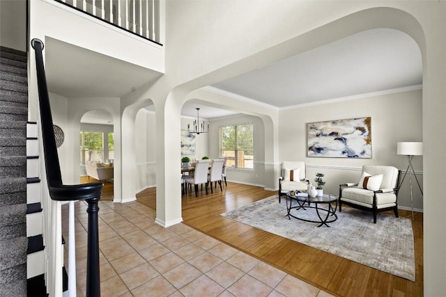 3416 Oxsheer Dr, Austin, TX 78732 - living room featuring light tile patterned floors, stairway, a chandelier, arched walkways, and crown molding