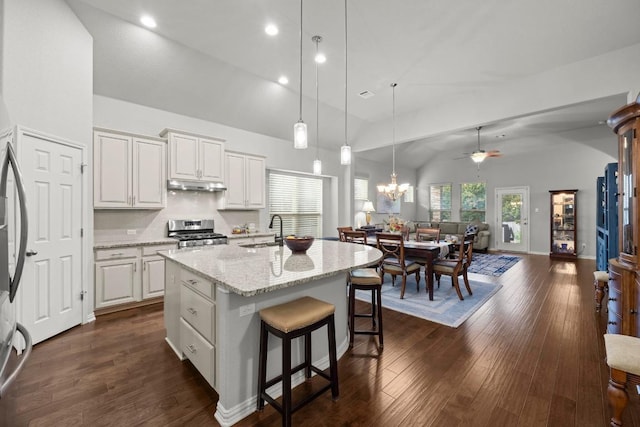 232 Mandana St, Leander, TX 78641 - kitchen featuring stainless steel range with gas stovetop, under cabinet range hood, white cabinets, hanging light fixtures, and light stone countertops