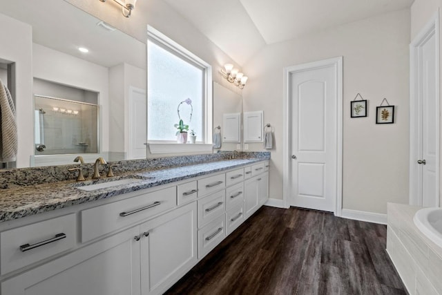 1329 Siena Sunset Rd, Leander, TX 78641 - bathroom with double vanity, a shower stall, a garden tub, and wood finished floors