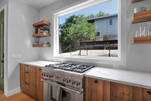1914 E 8th St, Austin, TX 78702 - kitchen with high end stove, open shelves, light wood-style flooring, brown cabinets, and modern cabinets